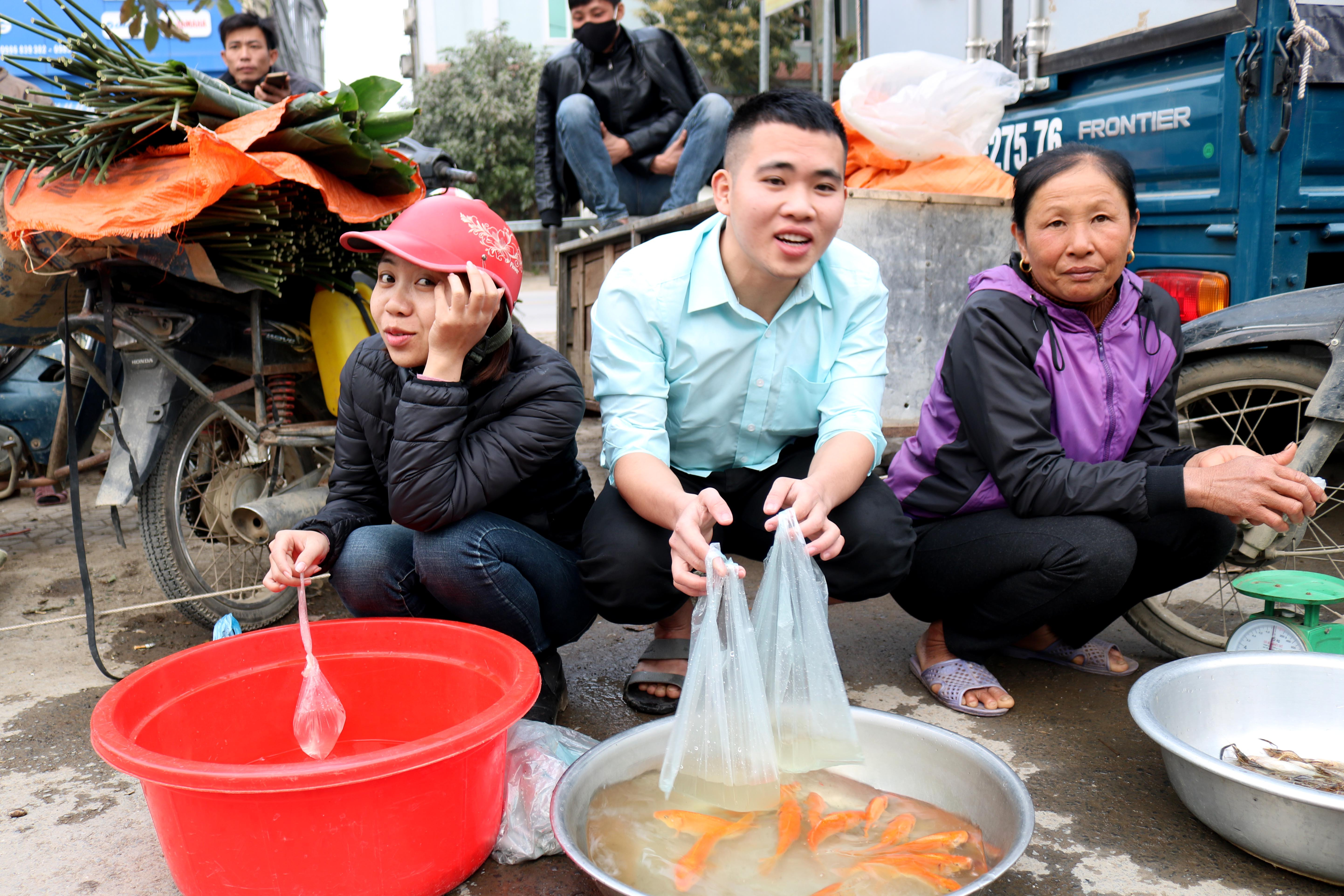 Nhiều bạn trẻ tham gia bán cá chép phụ giúp gia đình.  Hàng cá chép cúng lễ ở chợ quê đã bắt đầu rục rịch từ chiều 22 tháng chạp. Ảnh: Huy Thư