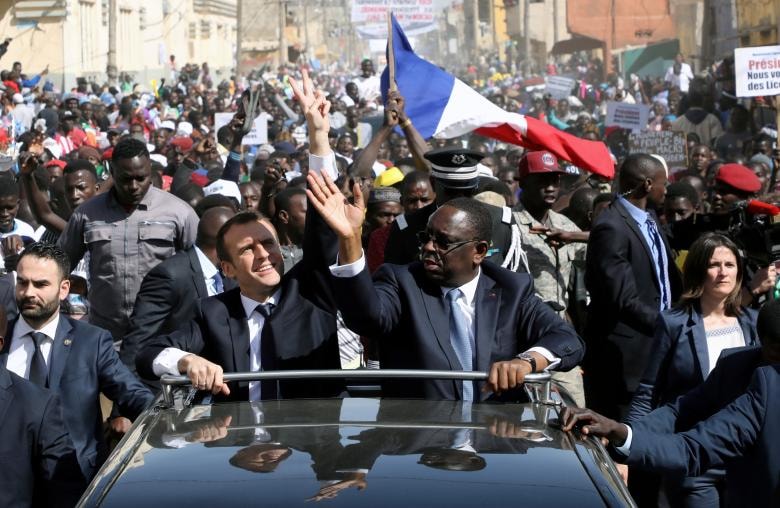 Tổng thống Pháp Emmanuel Macron và Chủ tịch Senegal Macky Sall vẫy tay chào đám đông từ một chiếc ô tô ở Saint-Louis, Senegal. 