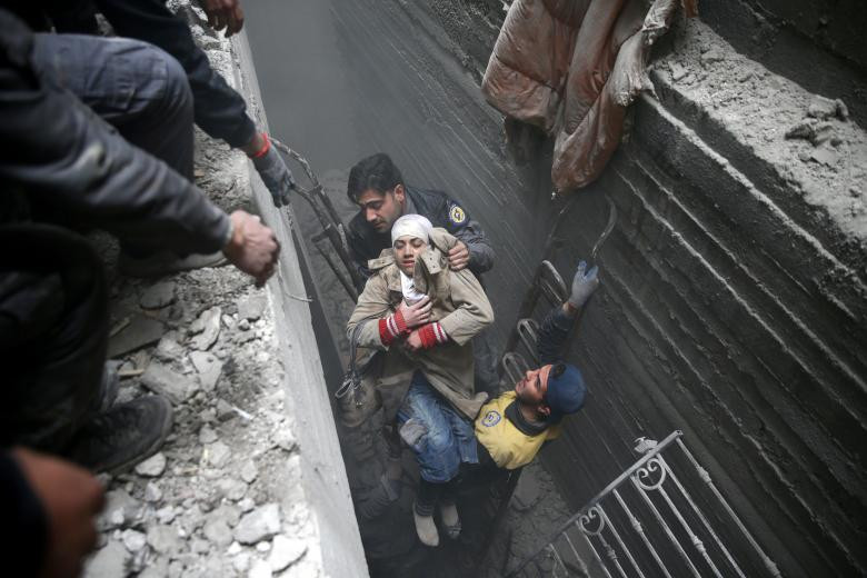 Các thành viên phòng vệ dân sự Syria giúp một người phụ nữ bất tỉnh từ một nơi trú ẩn ở thị trấn Douma, Đông Ghouta, Damascus, Syria.