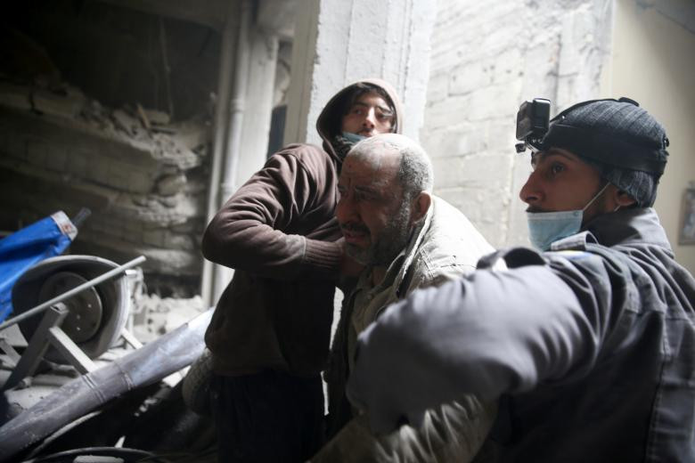 Bảo vệ dân sự giúp một người đàn ông từ một nơi trú ẩn tại thị trấn Douma bị bao vây ở phía đông Ghouta ở Damascus, ngày 22 tháng 2