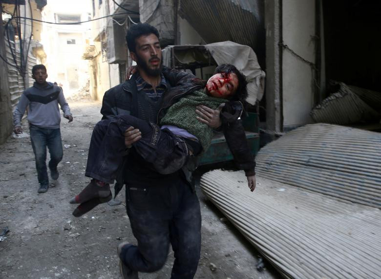 Một người đàn ông mang một cậu bé bị thương trong cuộc nổi dậy đã chiếm thành phố Hamouriyeh, đông Ghouta, gần Damascus, ngày 21 tháng 2