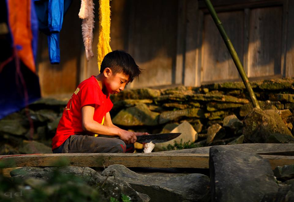 Một cậu bé loay hoay ngồi gọt chọi cù - một thú chơi của trẻ em Mông. Ảnh: Quốc Đàn