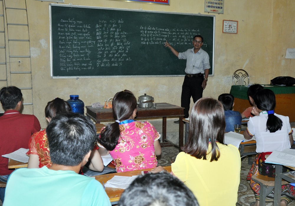 Nghệ nhân dân gian Vi Khăm Mun truyền dạy chữ Thái Lai Pao. Ảnh: Công Kiên