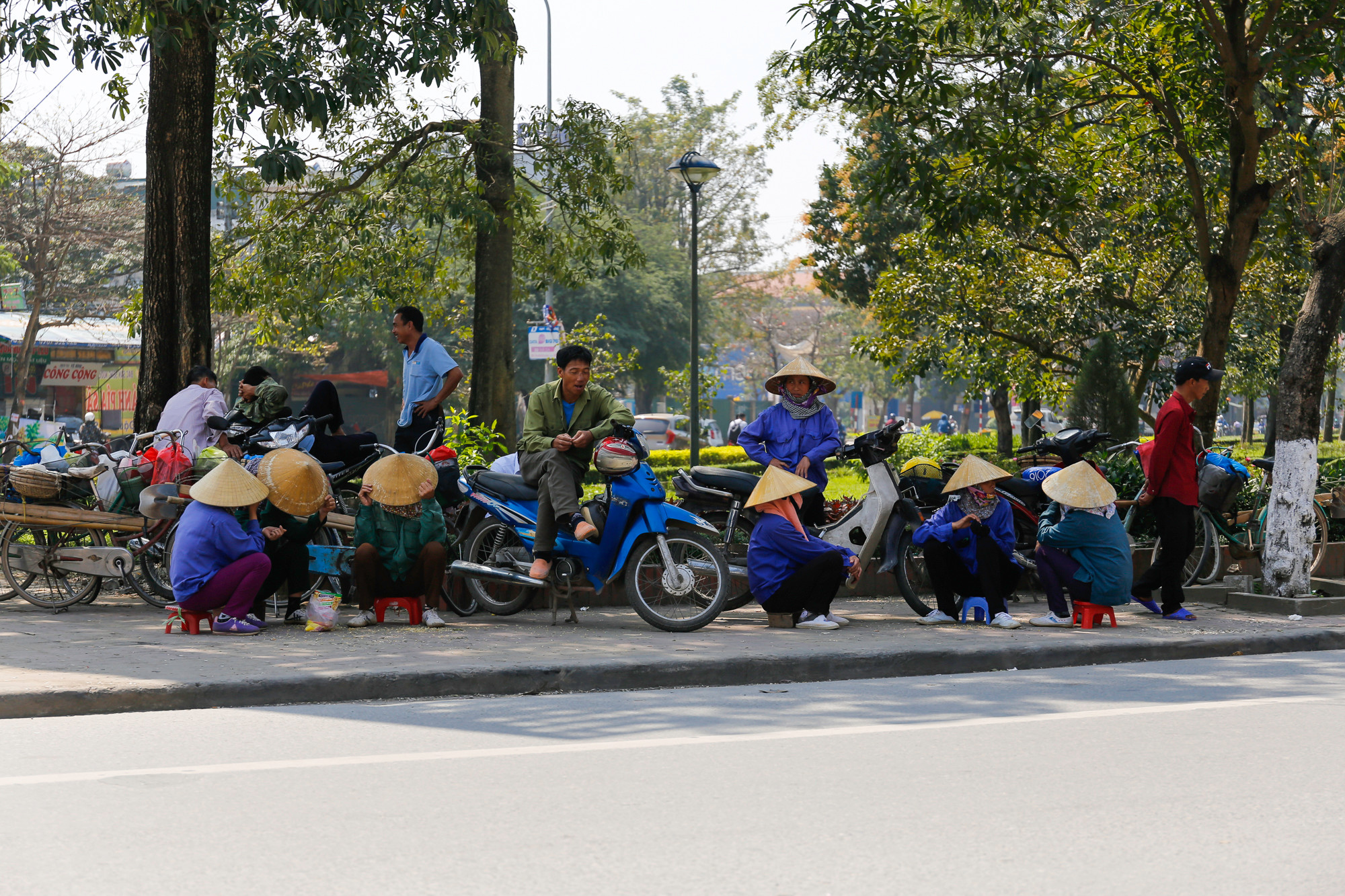 Tại công viên trên đường Nguyễn Thị Minh Khai những người làm nghề cửu vạn tìm chỗ im mát để chờ việc. Ảnh: Đức Anh