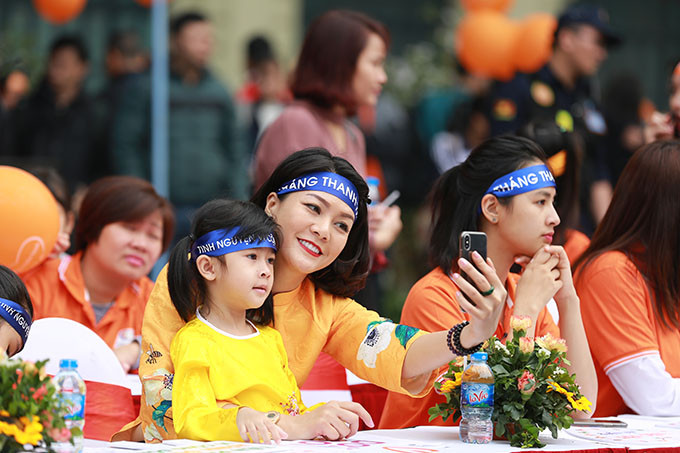 Hai mẹ con diễn viên Hoàng Xuân cũng có mặt từ sớm, diện áo dài vàng cam nổi bật và tích cực tham gia đi bộ cùng đoàn người tuần hành.
