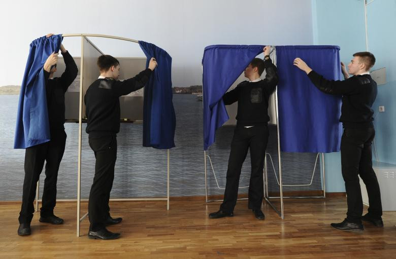 Các sinh viên điều chỉnh màn cửa buồng bỏ phiếu tại một phòng bỏ phiếu, đặt tại một trường cao đẳng chuyên chở nước, trong thời gian chuẩn bị cho cuộc bầu cử tổng thống sắp tới ở Rostov on Don, Nga ngày 16 tháng 3 năm 2018. 