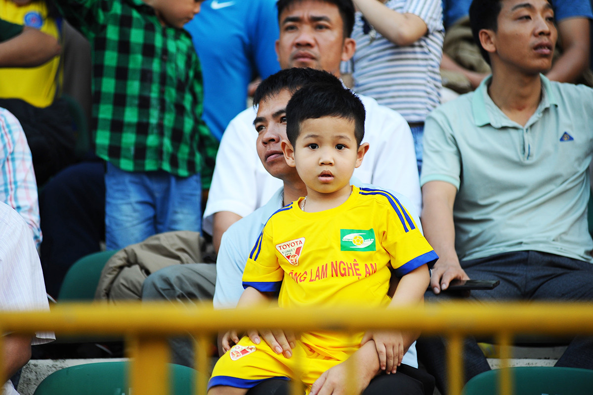 Một em bé trong vòng tay của bố cổ vũ cho đội bóng quê hương thi đấu. Ảnh: Trung Kiên