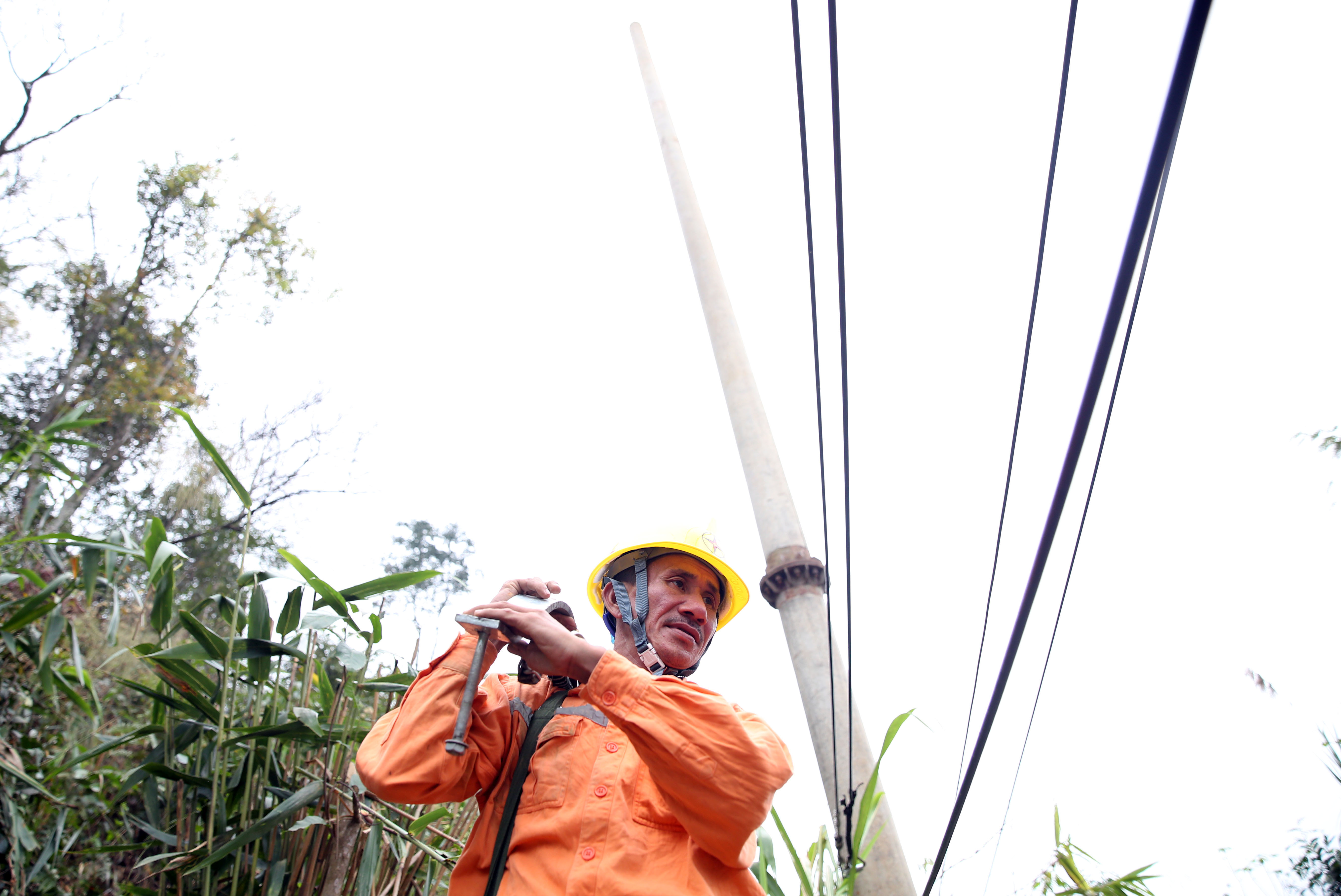 Cán bộ Điện lực Kỳ Sơn tháo dỡ đường dây điện tại quả đồi trong phạm vi có nguy cơ sạt lở. Ảnh: Hồ Phương