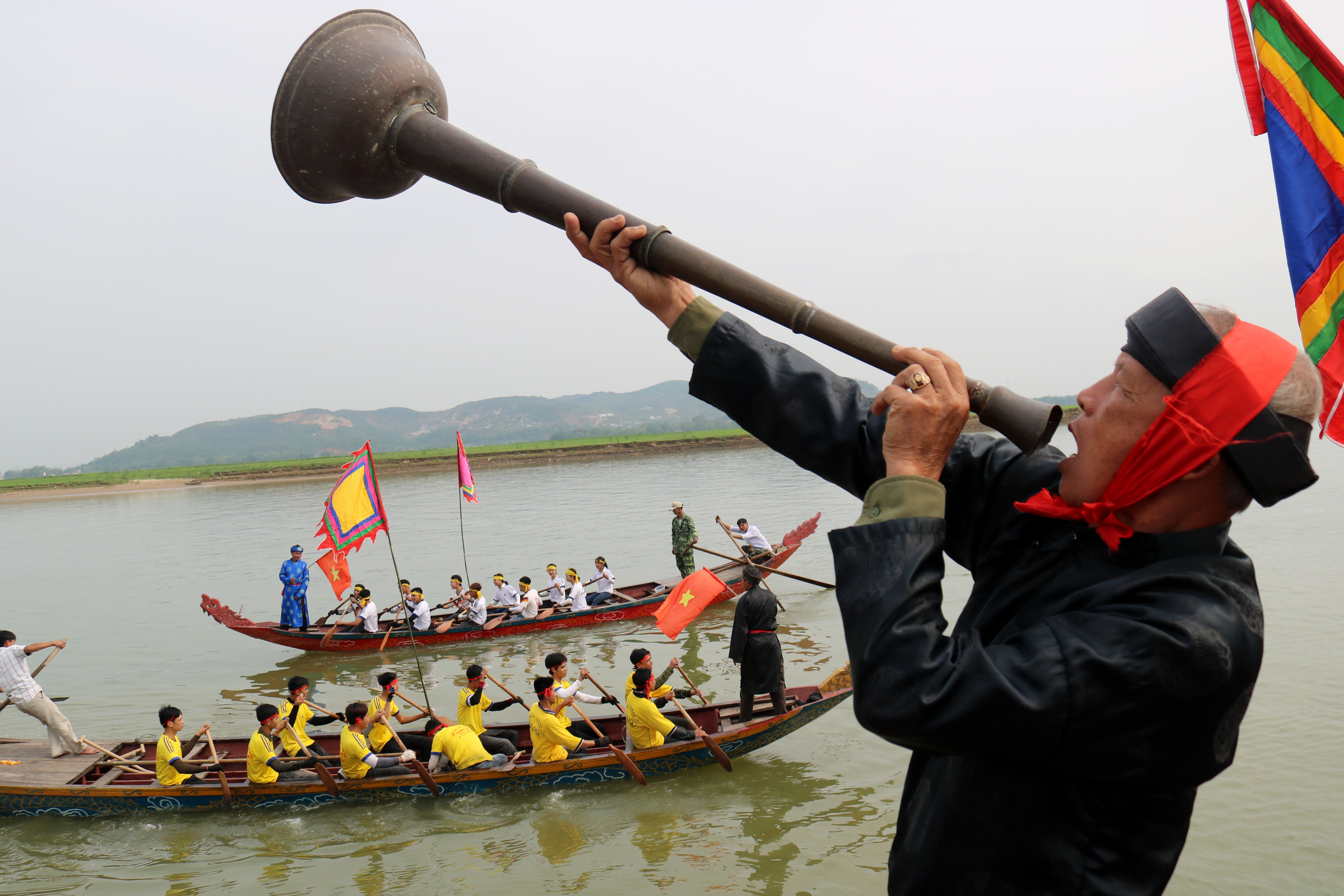 Trong khi lễ tế diễn ra, người dẫn đầu cầm loa đồng thúc các thuyền cùng chèo mạnh tay và reo hò quyết liệt. Ảnh: Huy Thư