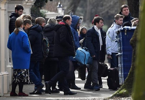 Các nhân viên ngoại giao Nga mang vác hành lý, đồ đạc đứng ngoài cổng Đại sứ quán Nga ở London. Ảnh: Reuters