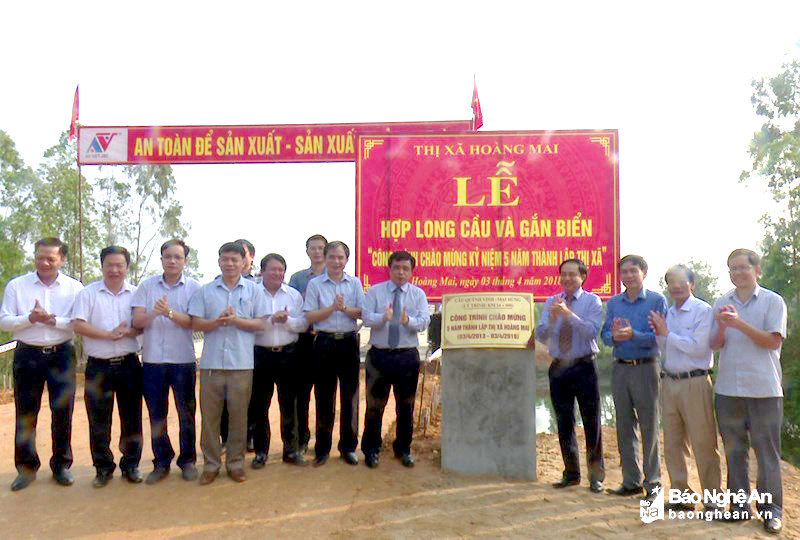 Các đại biểu gắn biển Kỷ niệm 5 năm thành lập thị xã tại công trình cầu qua sông Hoàng Mai từ Mai Hùng đi Quỳnh Vinh. Ảnh: Đình Trang