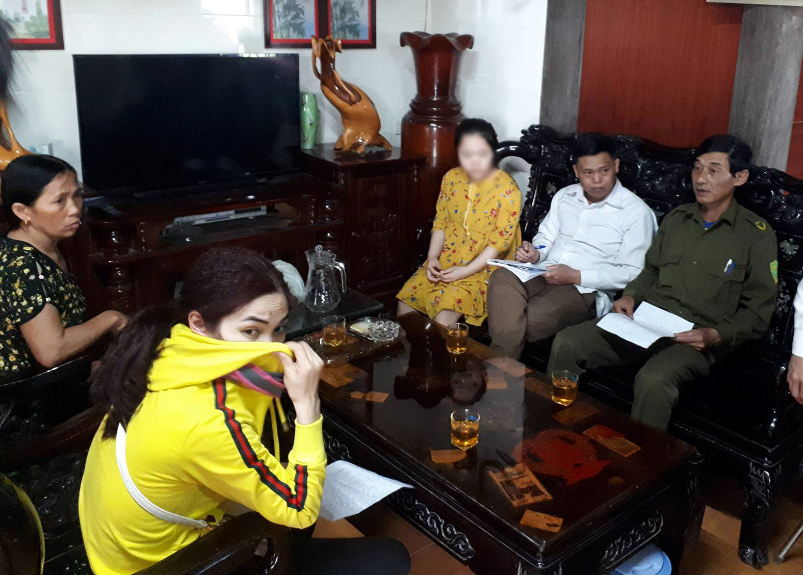 Bà Phan Thị Nghĩa liên tục lấy tay che mặt để tránh ống kính báo chí khi đến xin lỗi nạn nhân. Ảnh: Tiến Hùng