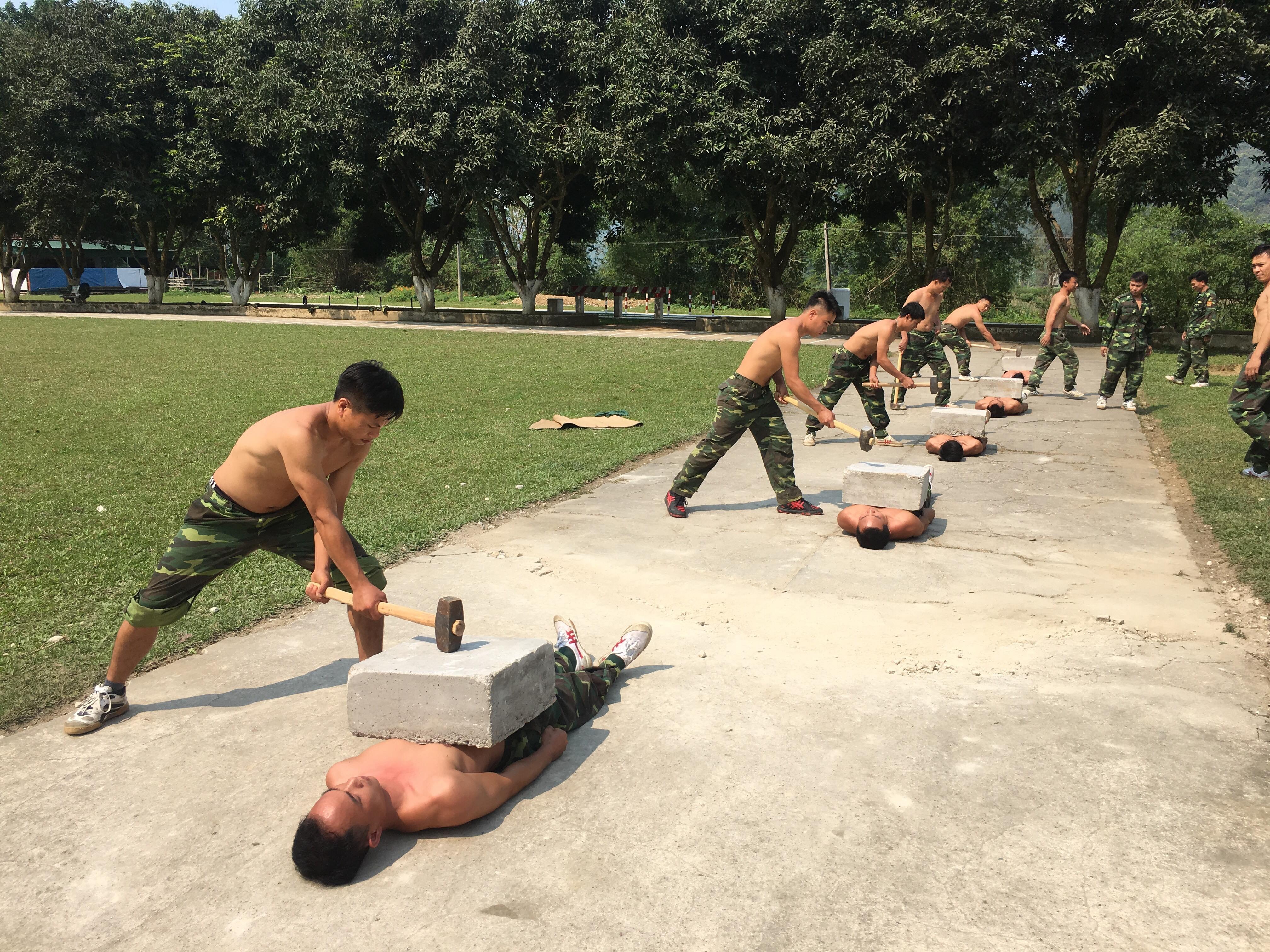 Những phiến đá được đặt lên bụng đã được nén khí công của các nam “võ sĩ” Biên phòng, có độ dày tới 20 phân và nặng tới 90 kg. Ảnh: Quân Doanh