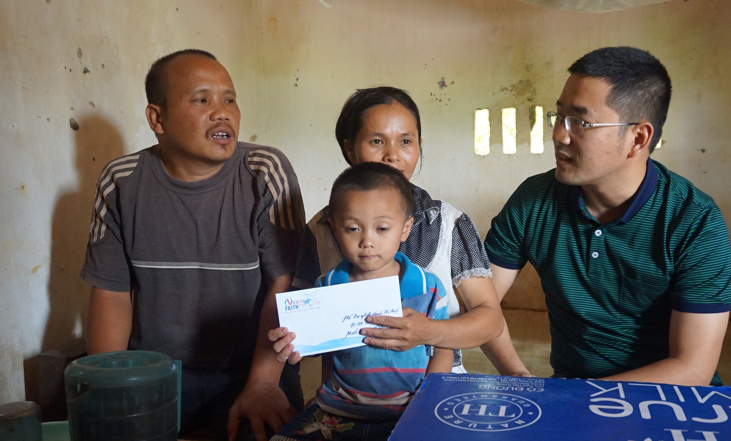 Gia đình anh Đặng Ngọc Chí nhận quà tặng và số tiền 10.000.000 đồng từ nhóm thiện nguyện Niềm tin (Faithgroup). Ảnh: Diệp Phương