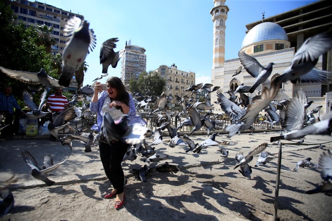 Một phụ nữ chụp ảnh selfie với đàn chim bồ câu ở quảng trưởng tại thủ đô. Ảnh Reuters.