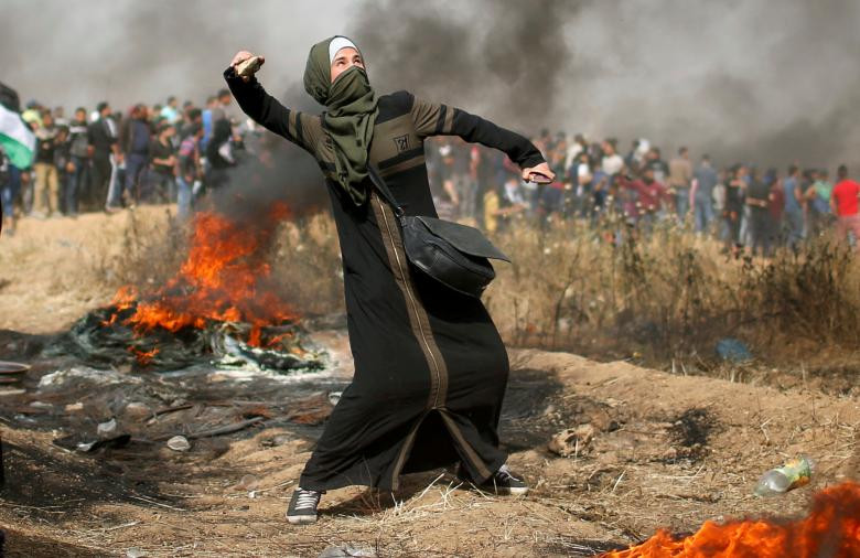 Cô gái ném đá trong các cuộc giao tranh với binh lính Israel sau khi nổ ra biểu tình và người Palestine đòi quyền trở về quê hương. Ảnh chụp tại ranh giới Israel-Gaza, phía đông thành phố Gaza hôm 13/4.