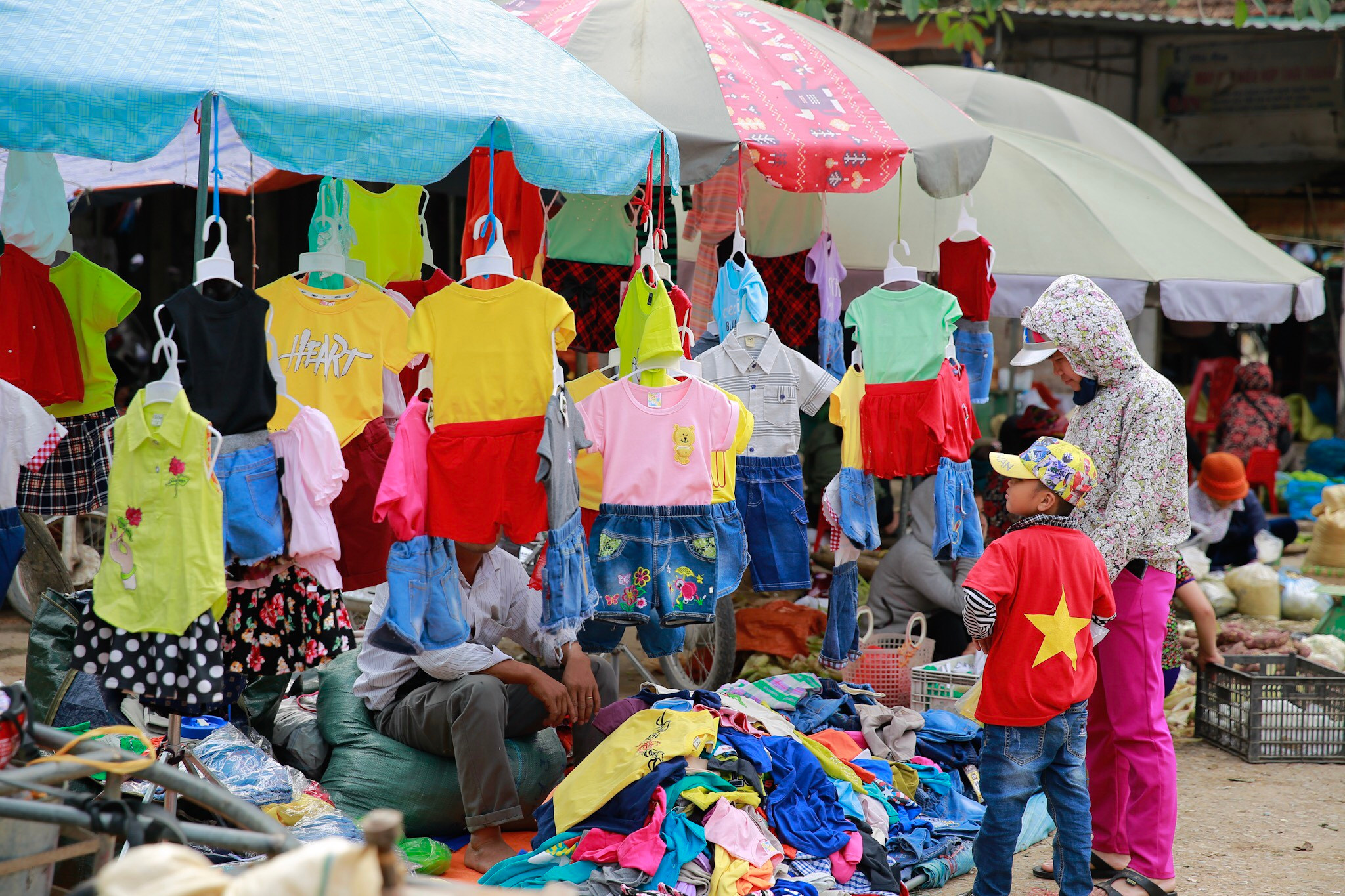 Một quầy quần áo trẻ em làm nên sắc màu sặc sỡ, bắt mắt giữa chợ. Ảnh: Hải Vương