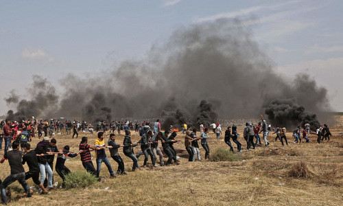 Người biểu tình Palestine tìm cách giật hàng rào thép gai. Ảnh: AFP