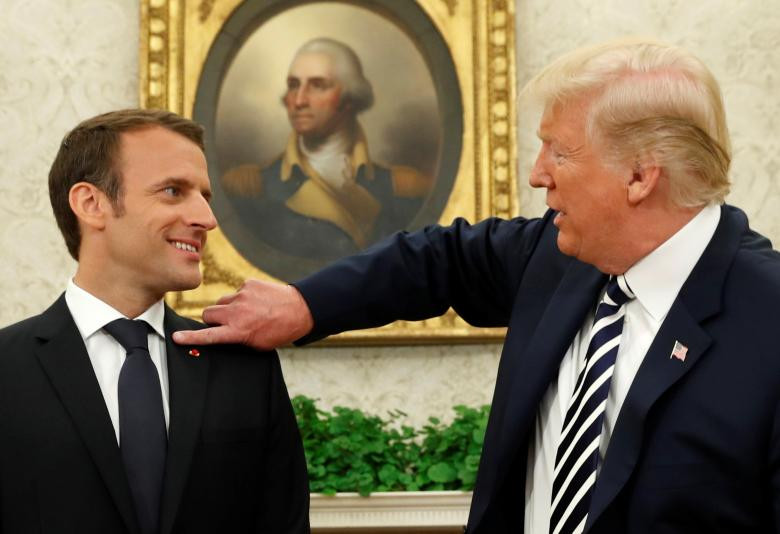 Tổng thống Pháp Emmanuel Macron (trái) ngước nhìn khi Tổng thống Mỹ Donald Trump phủi gàu dính trên áo khoác của mình trong cuộc gặp tại Phòng Bầu dục sau lễ đón chính thức dành cho ông Macron tại Nhà Trắng ở Washington hôm 24/4.