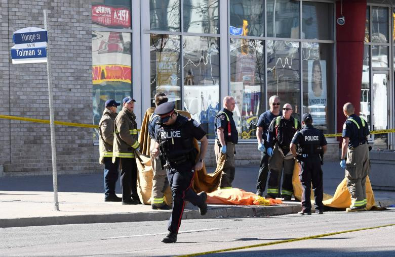 Lính cứu hỏa đứng gần một thi thể đã được che đậy sau khi một chiếc xe đâm vào nhiều người tại giao lộ lớn ở phía Bắc Toronto,Ontario, Canada hôm 23/4.