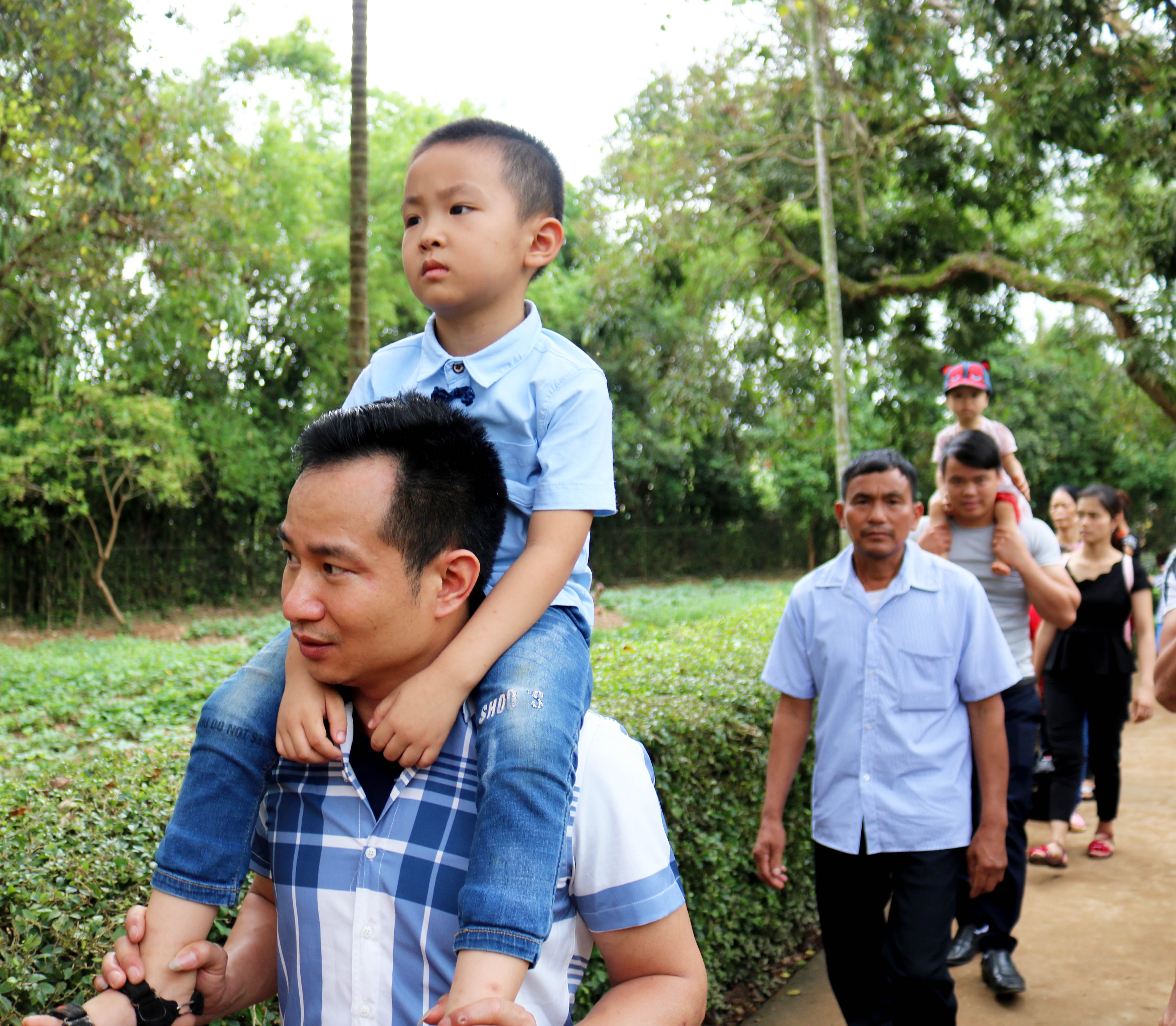 Những cháu bé được người lớn cho “cưỡi cổ” để thuận tiện di chuyển trong dòng người đông đúc. Ảnh: Huy Thư