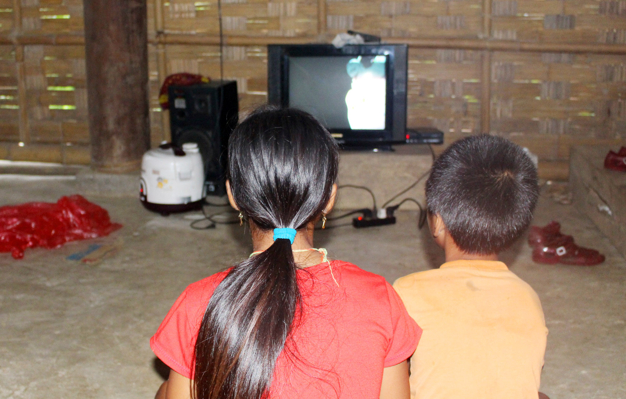 Hai đứa trẻ trong một gia đình ở bản Cò Phạt mải mê với những ngày đầu tiên được xem ti vi. ảnh : Bá Hậu
