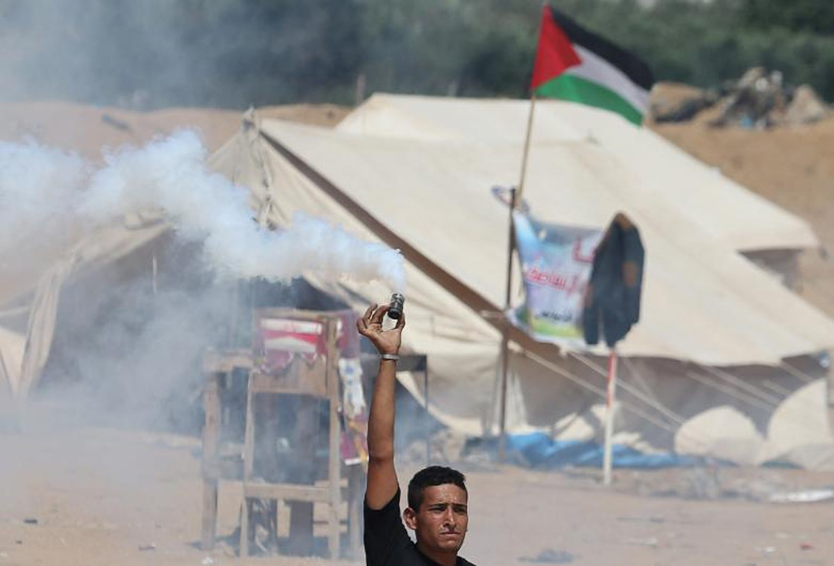 Một người Palestine cầm bình gas rách do lực lượng Israel bắn ra trong một cuộc biểu tình tại biên giới Israel - Gaza. Ảnh: Reuters