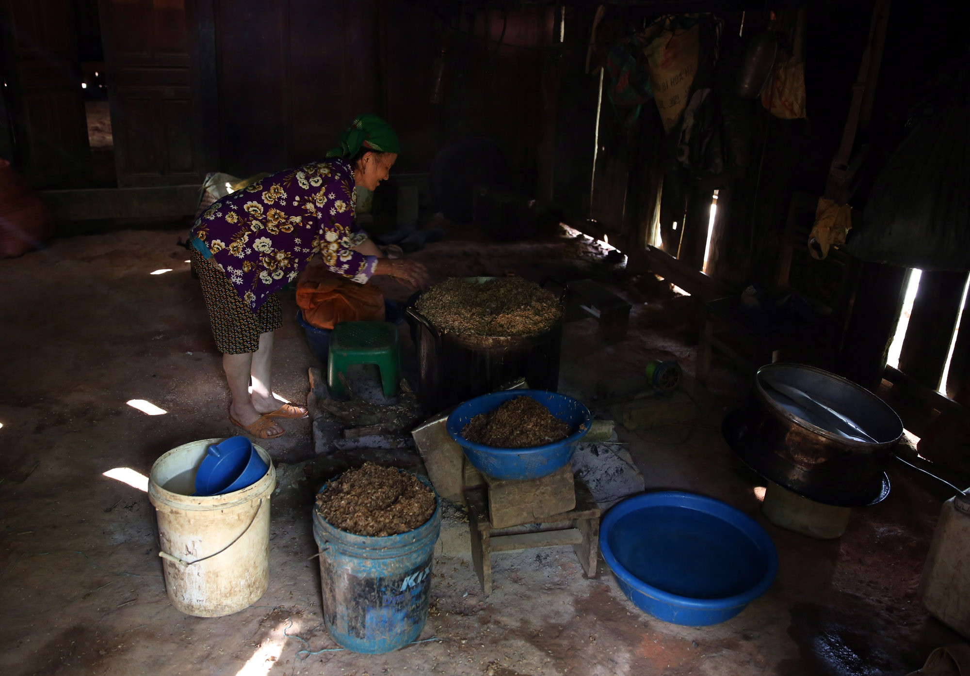 TRong nhà, một người phụ nữ Mông đang nấu rượu, công việc này đã được những phụ nữ duy trì qua nhiều thế hệ. : Ảnh : Hồ Phương