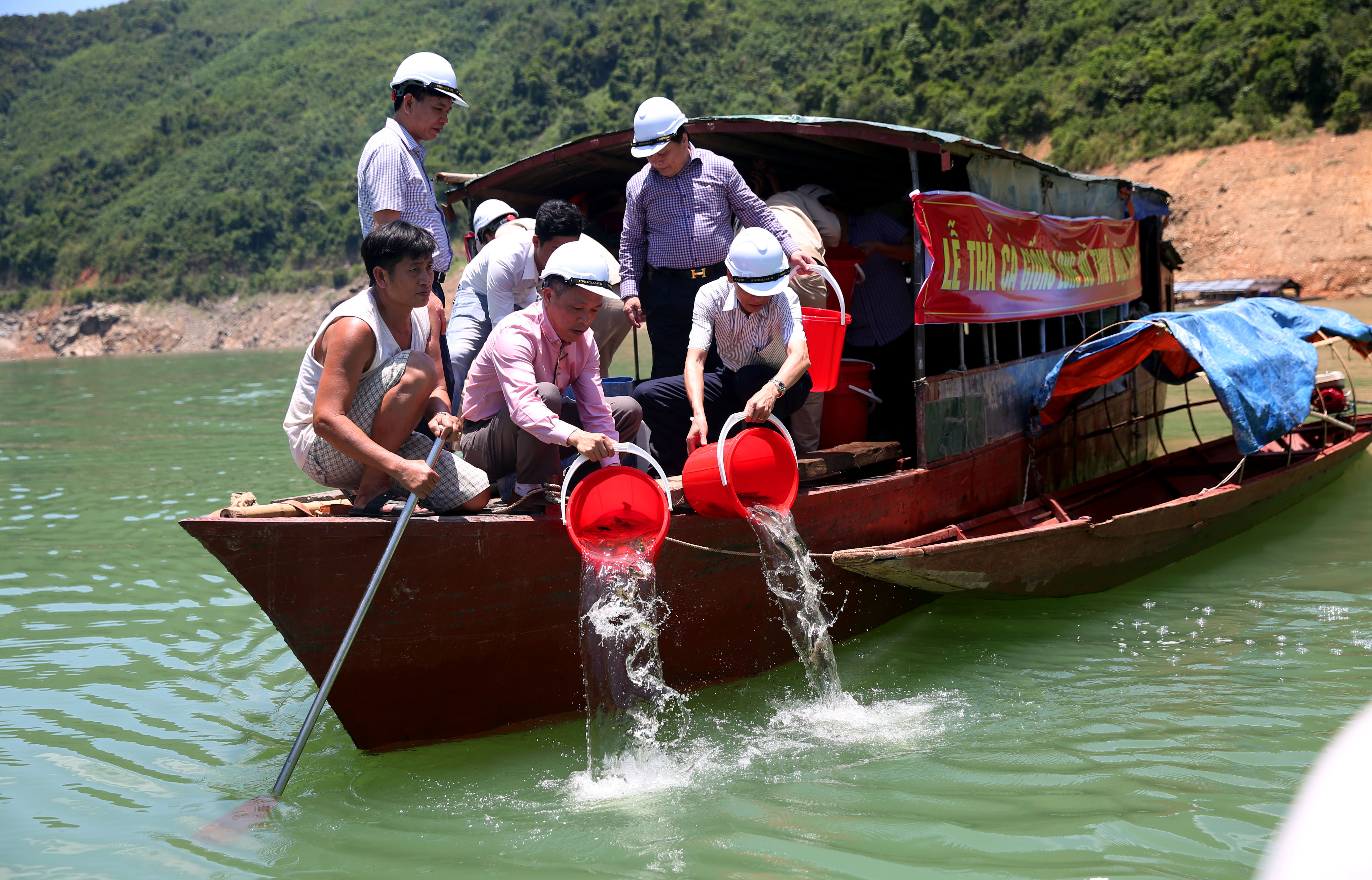 Đại diện Công ty thủy điện Bản Vẽ thả cá xuống lòng hồ. Ảnh: Hồ Phương