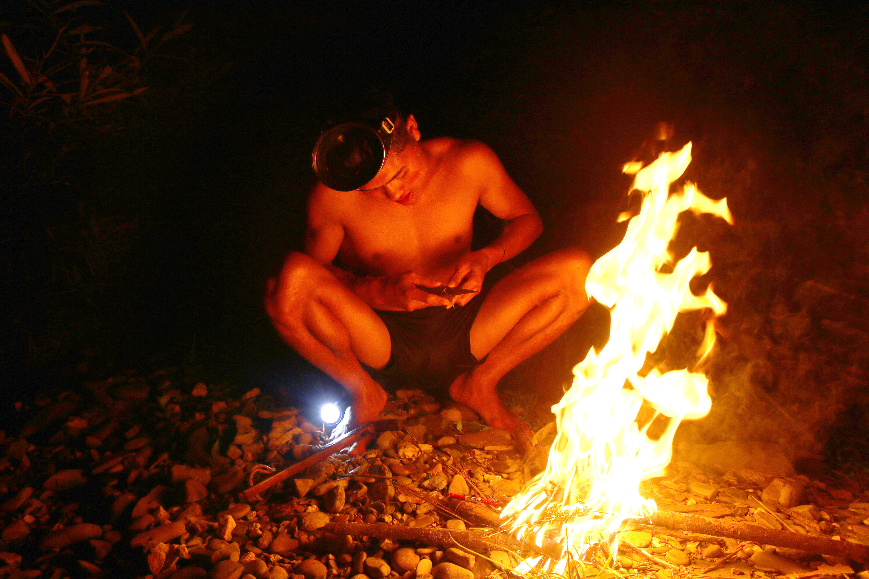 Một chàng trai Khơ Mú đốt lửa vót mũi tên dưới ánh lửa để chuẩn bị cho cuộc đi săn. Ảnh: Đào Thọ
