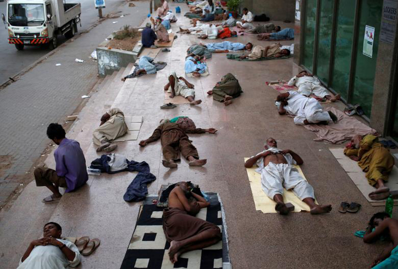 Cư dân ngủ trên vỉa hè của tòa nhà, để thoát khỏi sức nóng và mất điện thường xuyên trong khu vực cư trú của họ Karachi, Pakistan. Ảnh: Reuters