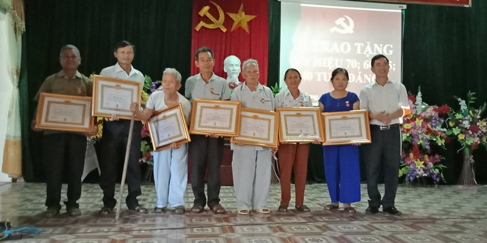Trao Huy hiệu 70 năm tuổi Đảng cho đồng chí Hoa Văn Hiến (thứ 5 từ trái sang) và các đảng viên tại xã Nghĩa Hưng. Ảnh: Minh Thái