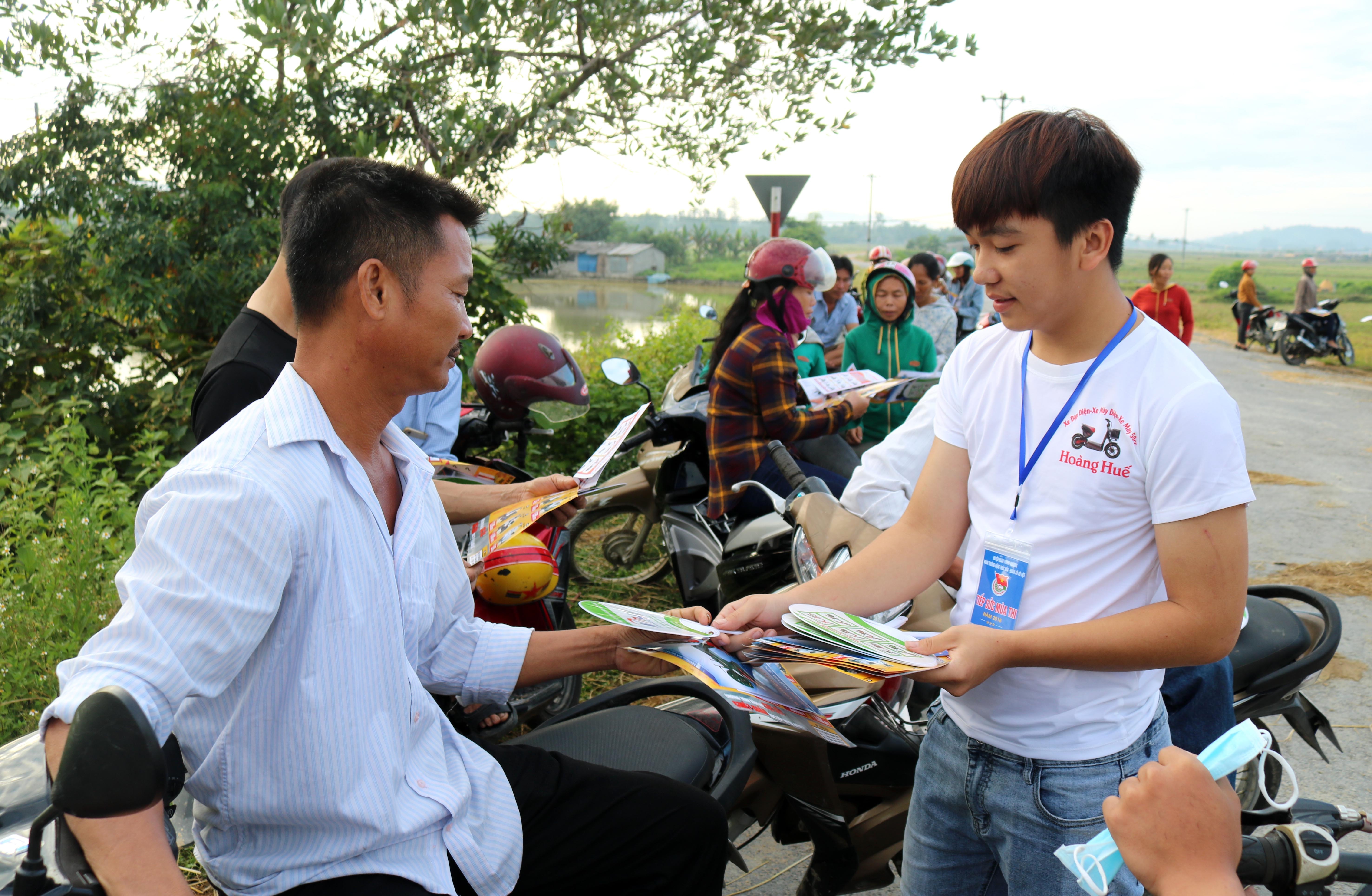 Chờ con em đi thi giữa nắng hè gay gắt, các phụ huynh quanh các điểm thi được các tình nguyện viên phát quạt nhựa miễn phí. Ảnh: Huy Thư