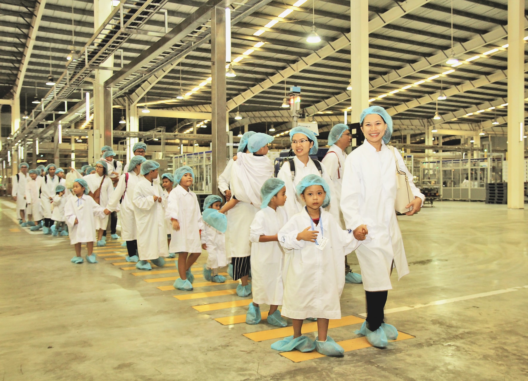 Các bé được các nhân viên hướng dẫn tham quan bên trong nhà máy. Ảnh: H.H
