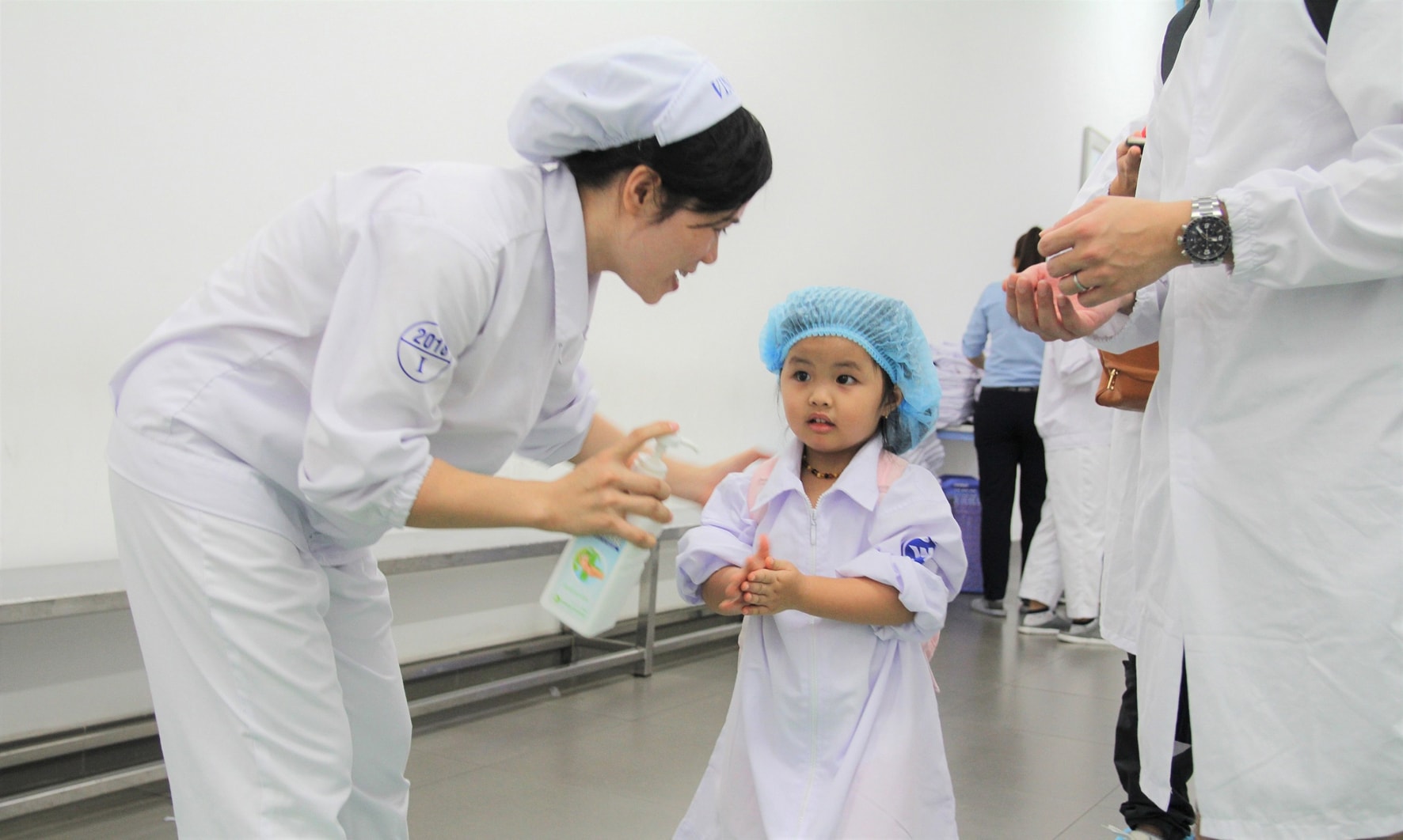 Trước khi vào tham quan, các bạn nhỏ được các cô chú nhân viên tại nhà máy hướng dẫn về cách di chuyển trong nhà máy, mặc trang phục bảo hộ và rửa tay đúng theo quy định của nhà máy. Ảnh: H.H