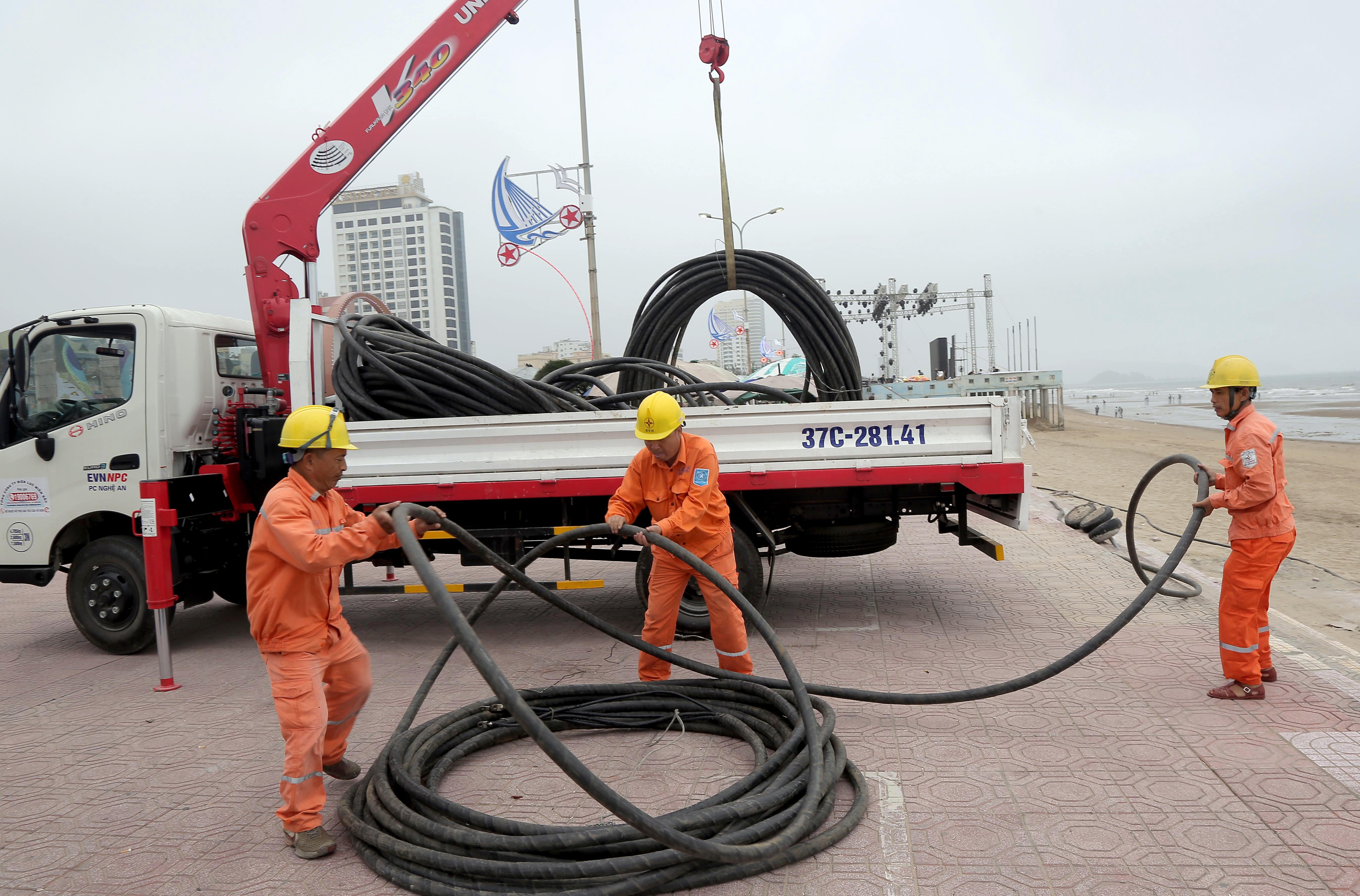 Công nhân Công ty Điện lực Nghệ An kéo đường dây điện phục vụ Lễ hội du lịch Cửa Lò. Ảnh: Hoàng Hảo 