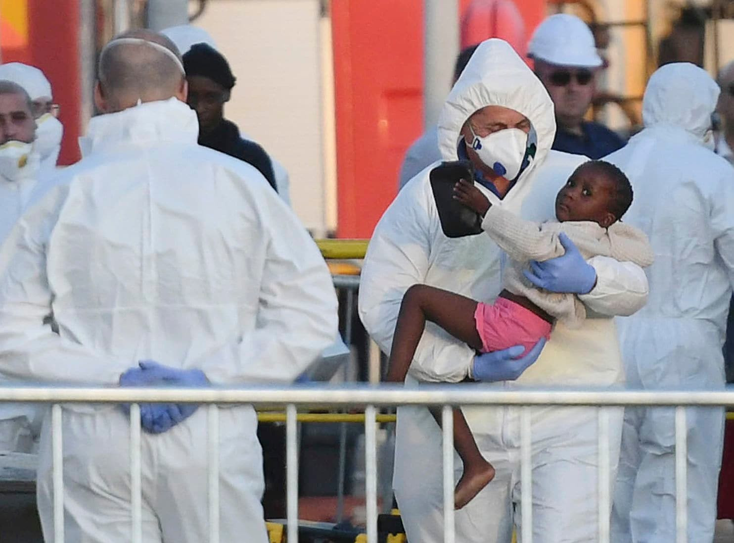 Một đứa trẻ được đưa xuống từ con tàu chở 234 người di cư sau khi cập cảng tại Malta hôm 27/6. Ảnh: AP