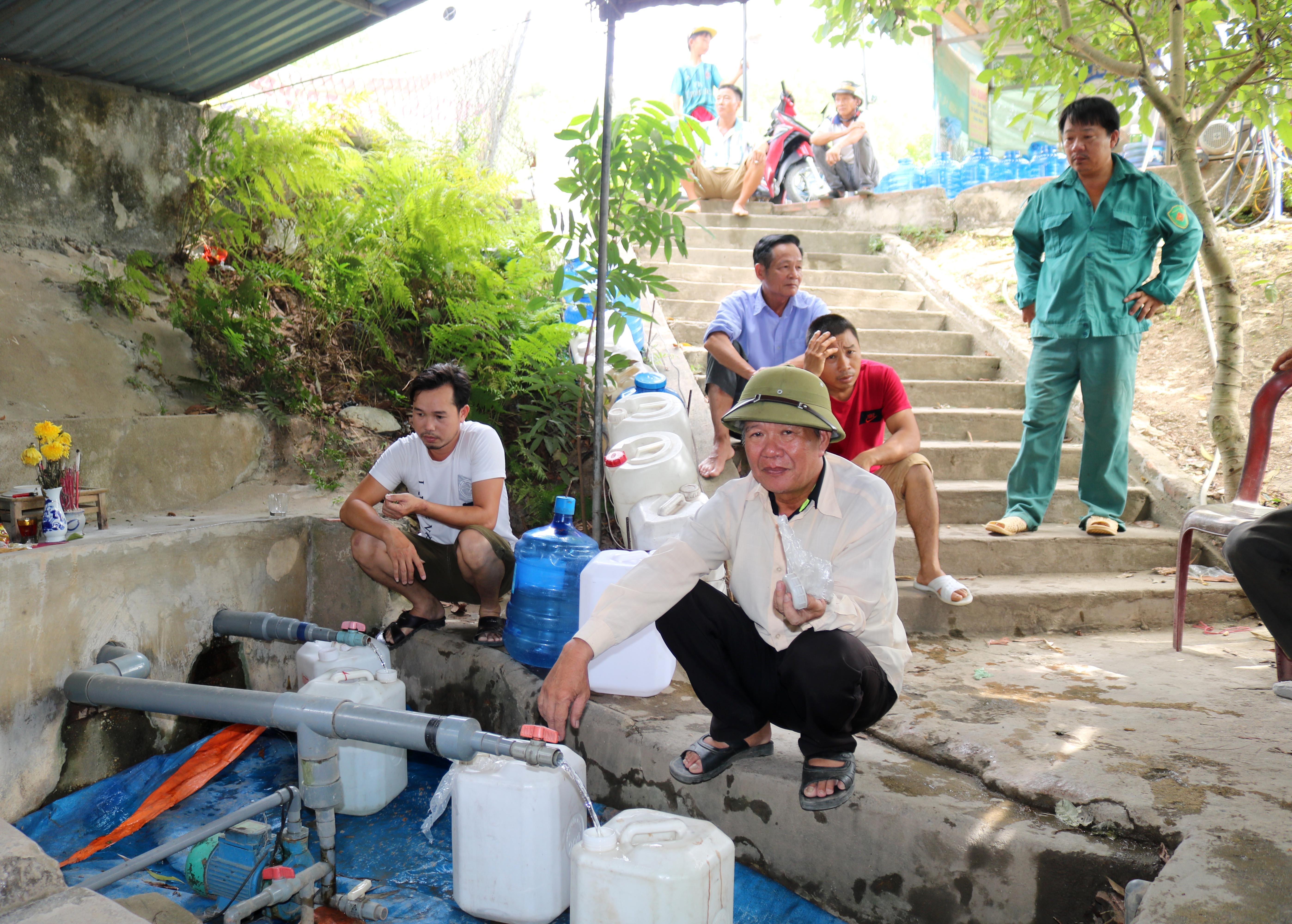 Giữa trưa, người dân vẫn kiên trì ngồi chờ để lấy nước Cống Kẹp. Ảnh: Huy Thư