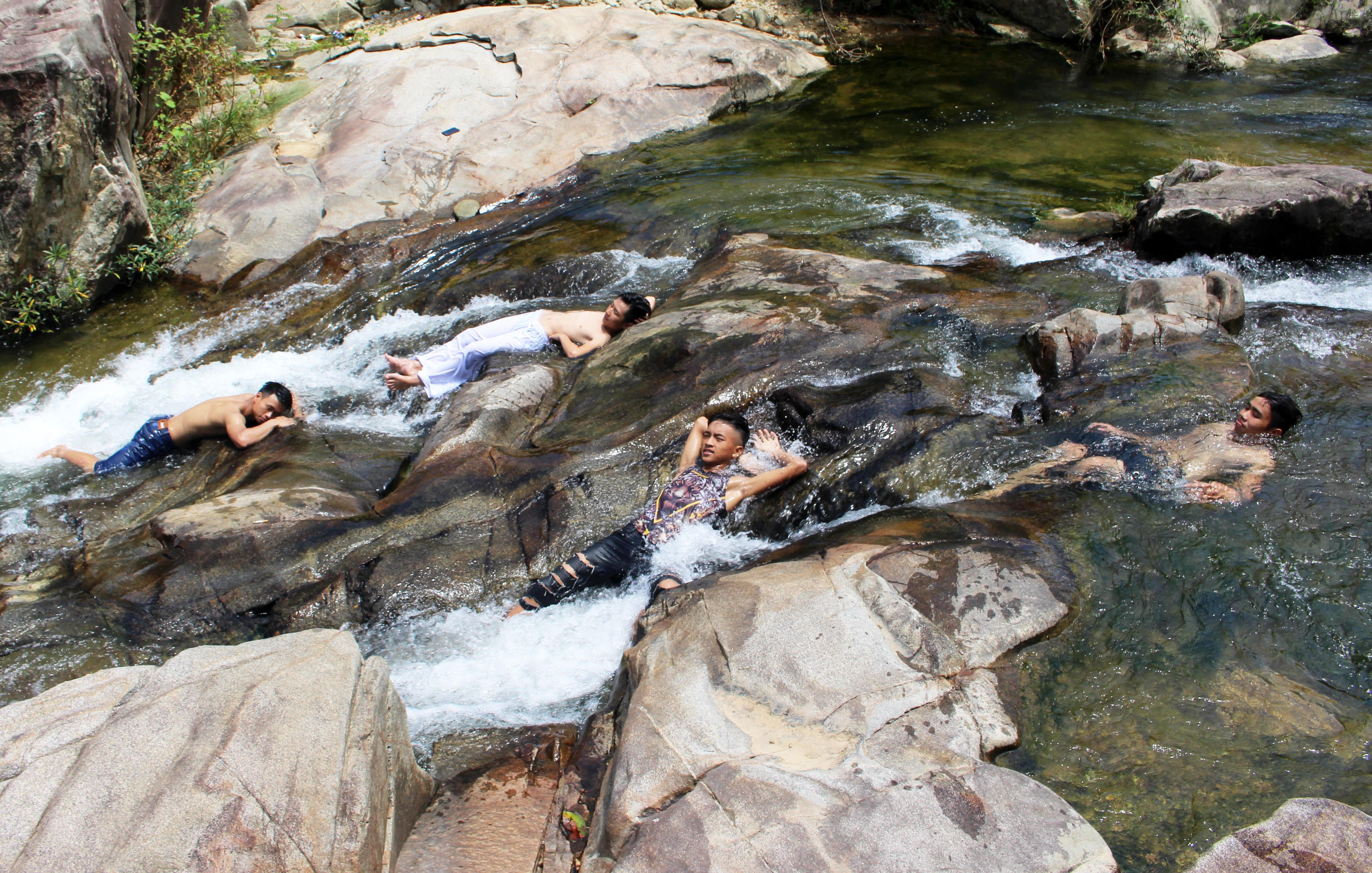 Những bạn trẻ thích thú thả mình trên những bãi đá nhấp nhô ở thác Cây Đa (Thanh Chương), để đón dòng nước mát trườn qua thân thể. Ảnh: Huy Thư
