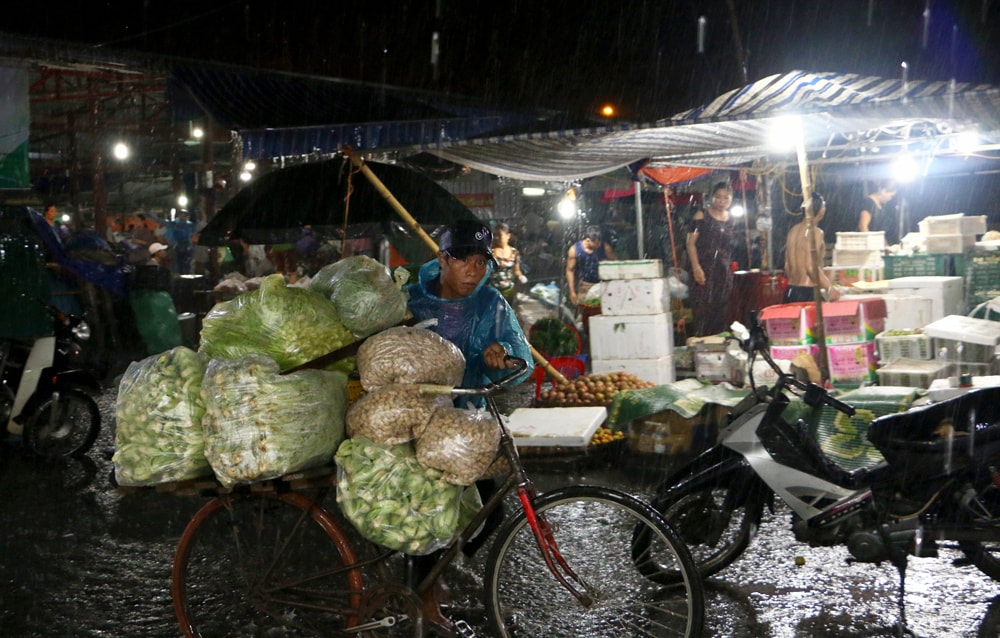 Việc bốc giỡ và vận chuyển hàng hóa trở nên khó khăn khi cơn mưa ngày càng lớn. Ảnh: Lâm Tùng