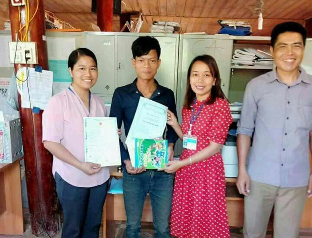 Cán bộ một văn phòng xã Mai Sơn gửi tặng quà cho một công dân mới chào đời qua người bố. Ảnh: B. T. Lan