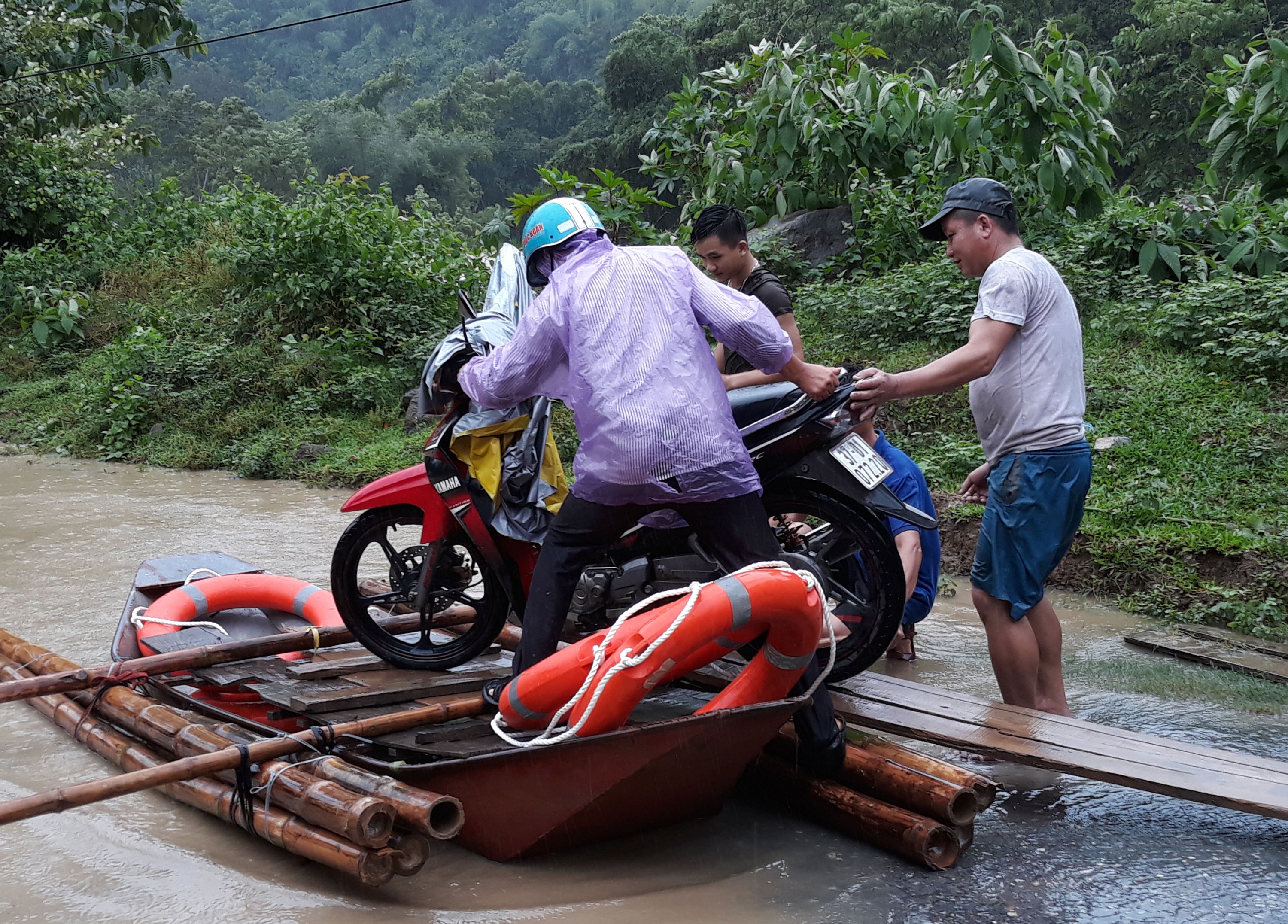 Trên đoạn đường ở bản Khe Kiền vào xã Nậm Càn nước ngập sâu đến ngực nên nhiều người phải kết bè để phục vụ người và xe qua lại được dễ dàng hơn. Ảnh: Đào Thọ