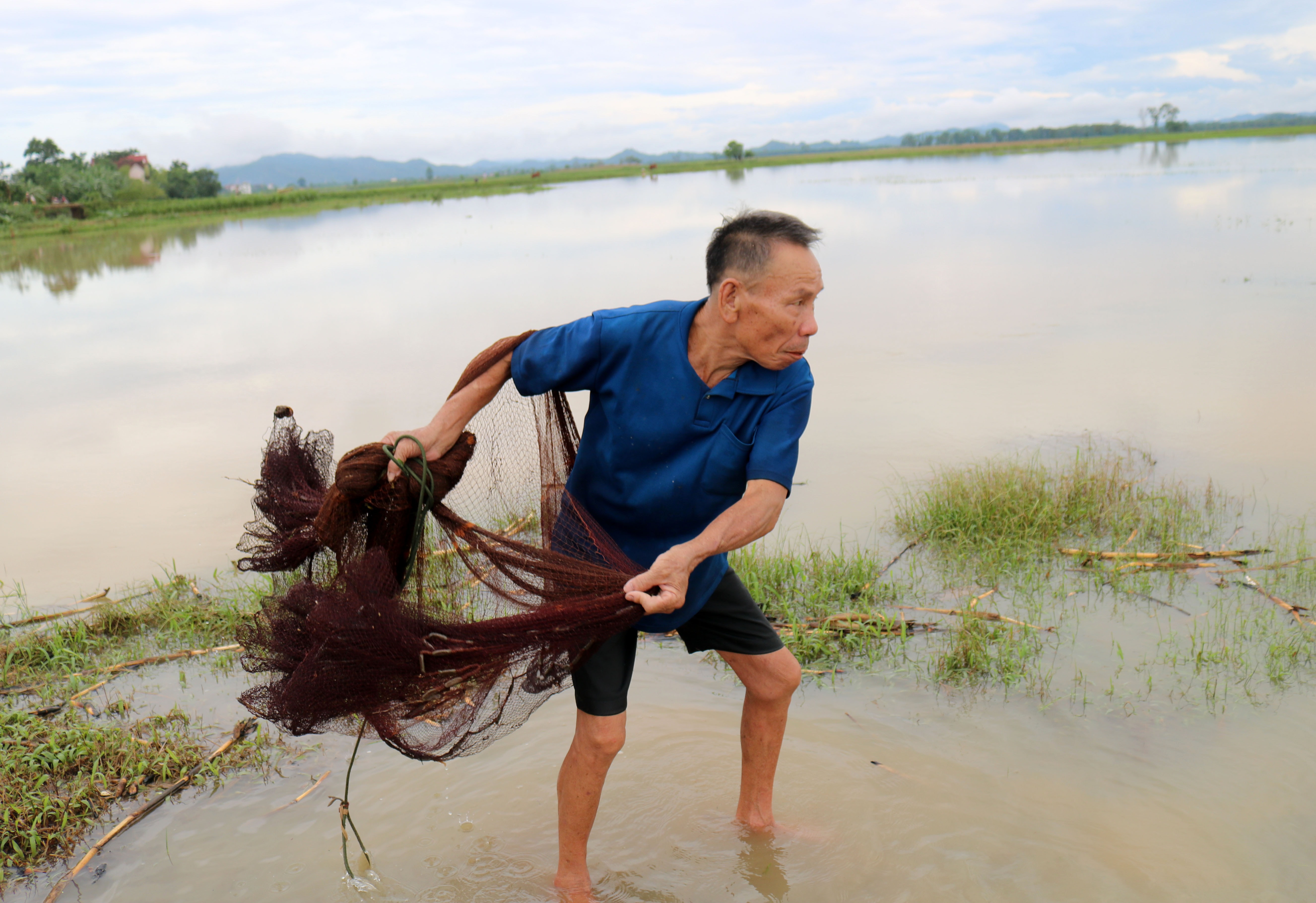 Một cụ ông đã ngoài “thất thập” nhưng vẫn tích cực đi ra ruộng, trông con nước, xem tăm cá để vãi chài. Ảnh: Huy Thư