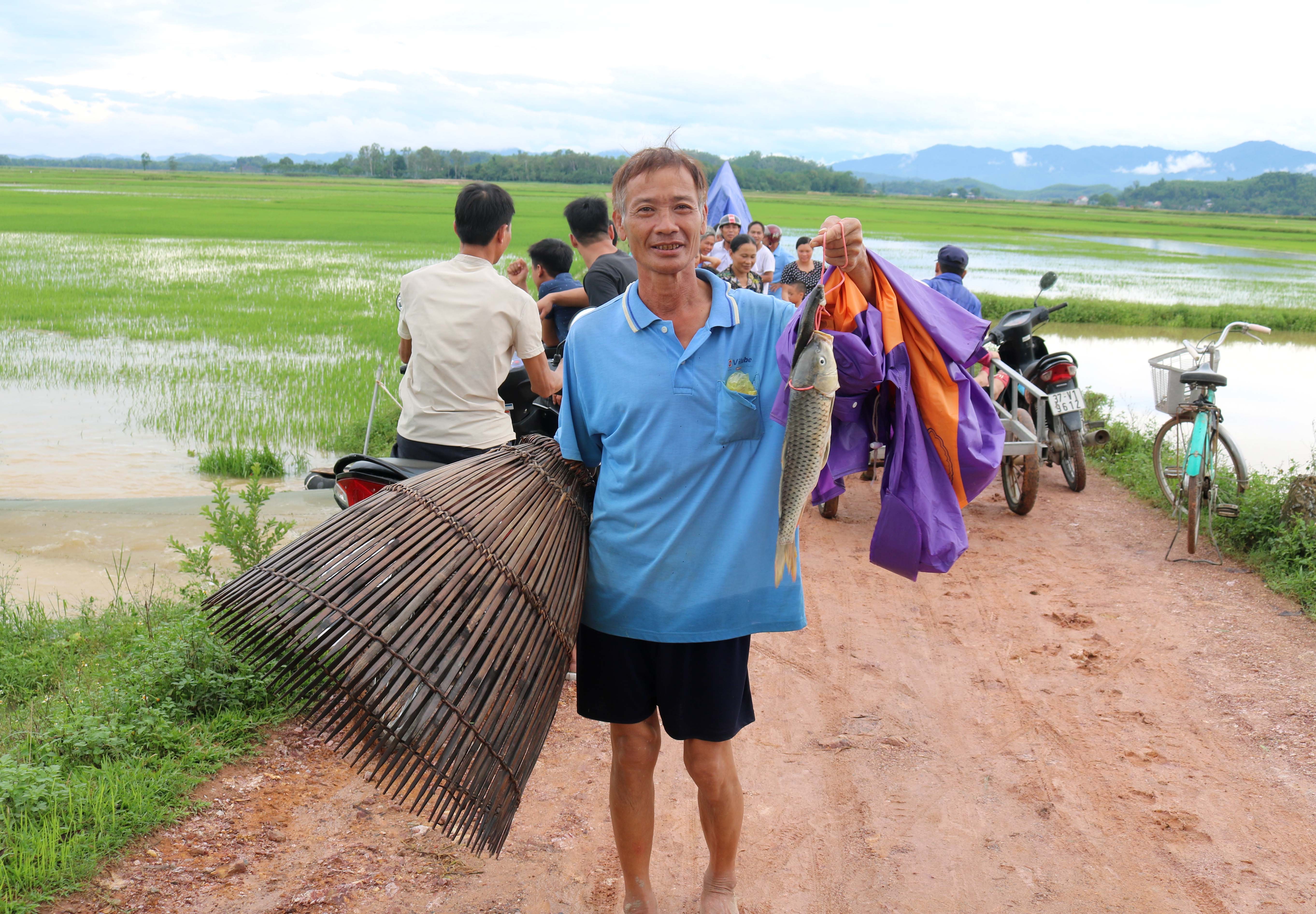 Ngày trời mưa nhiều người còn mang nơm ra đồng kiên trì  chờ cá ngược nước để chụp. Ảnh: Huy Thư