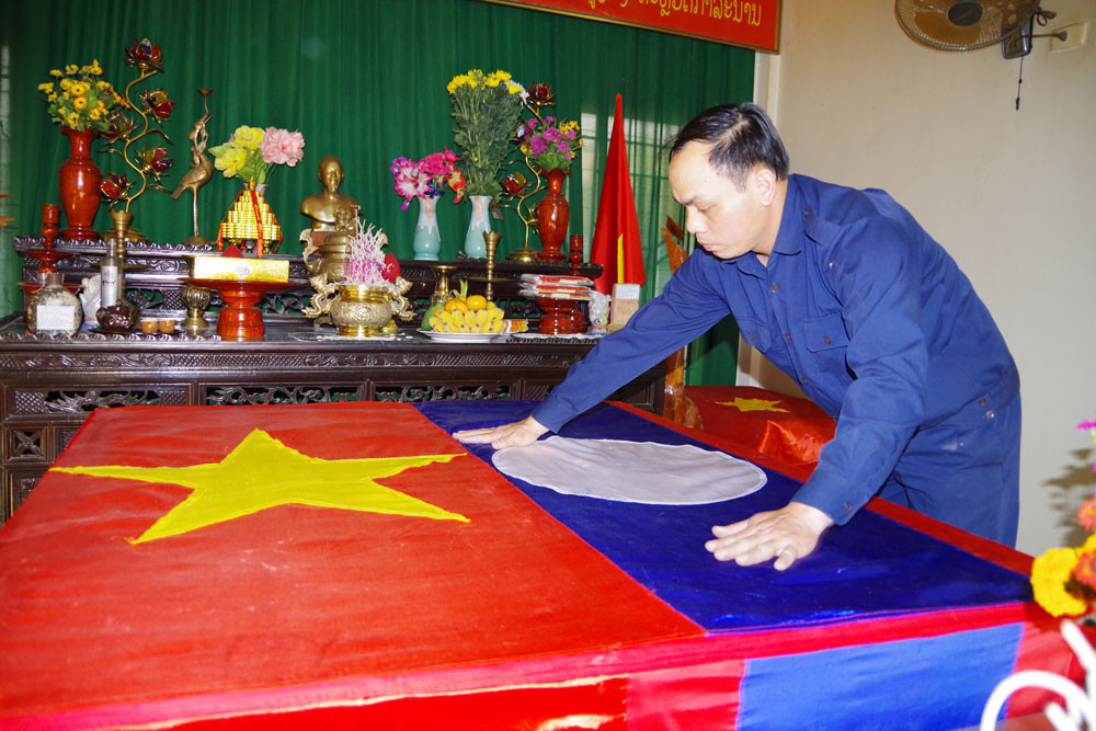 Đồng đội chăm sóc và phủ Quốc kỳ hai nước Việt Nam - Lào lên hài cốt liệt sỹ hy sinh vì nhiệm vụ quốc tế cao cả. Ảnh: Trọng Kiên