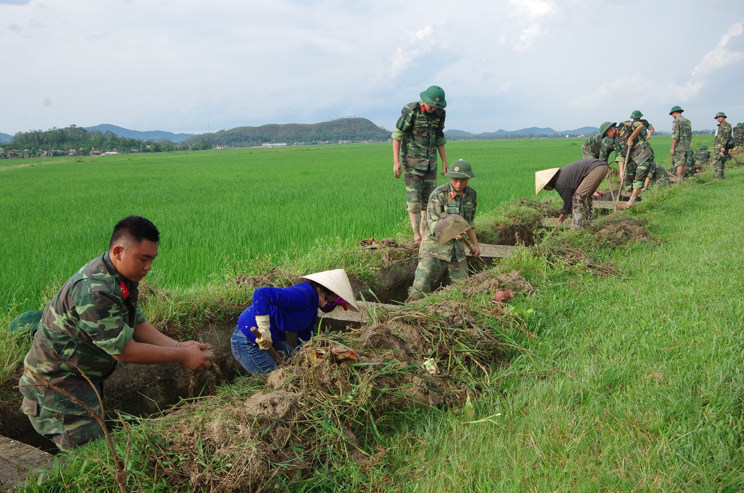 Cán bộ, chiến sỹ Trung đoàn 764 cùng đoàn viên thanh niên và nhân dân xã Nghi Công Nam đang nạo vét, khai thông tuyến kênh thủy lợi nội đồng. Ảnh: Phong Quang