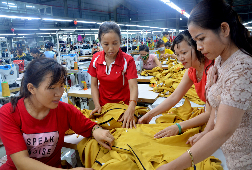 Chị Ngô Thị Thương (ngoài cùng, bên phải) Phó Giám đốc công ty trao đổi kỹ thuật với các chuyền may. Ảnh: Lương Mai