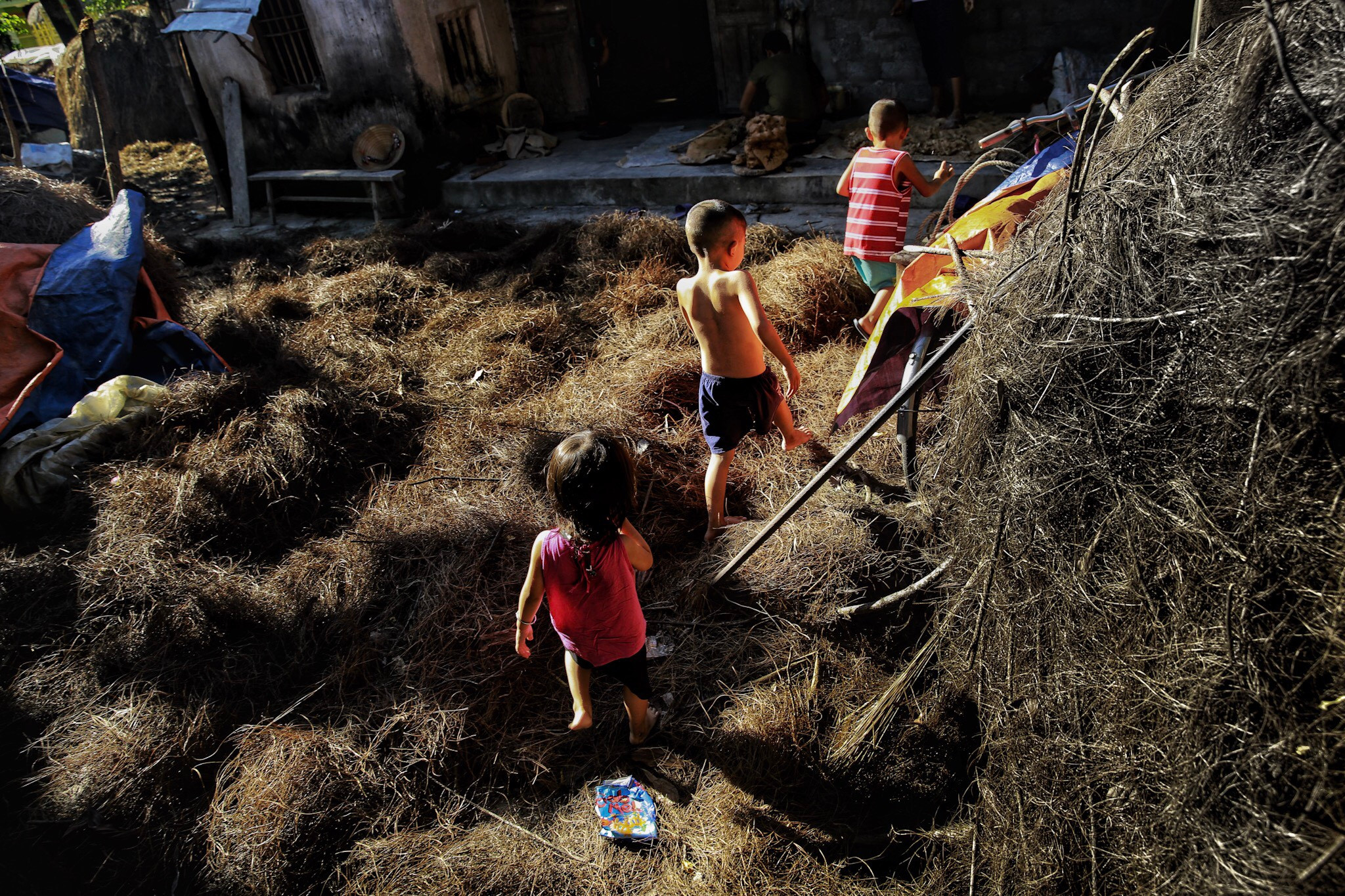 Lũ trẻ chơi đùa giữa những đụn rơm khô phơi đầy sân nhà. Ảnh: Hải Vương