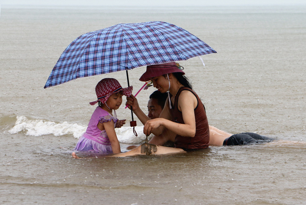 Một gia đình mang cả ô ra biển để chơi đùa. Ảnh: Lâm Tùng