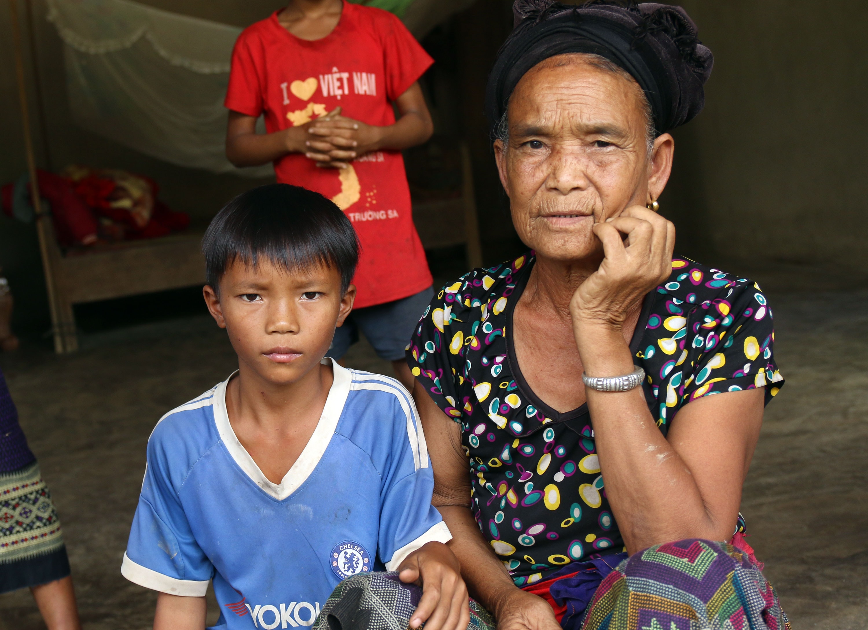 Cháu Moong Văn Cường, con anh Lợi ngồi nép mình bên bà nội. Ảnh: Thọ Tuân